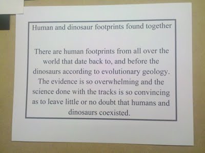 Sign reads: Human and dinosaur footprints found together. There are human footprints from all over the world that date back to, and before the dinosaurs according to evolutionary geology. The evidence is so overwhelming and the science done with the tracks is so convincing as to leave little or no doubt that humans and dinosaurs coexisted.